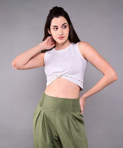 A woman wears the White Twisted Crop Top with green pants, posing against a plain gray background.