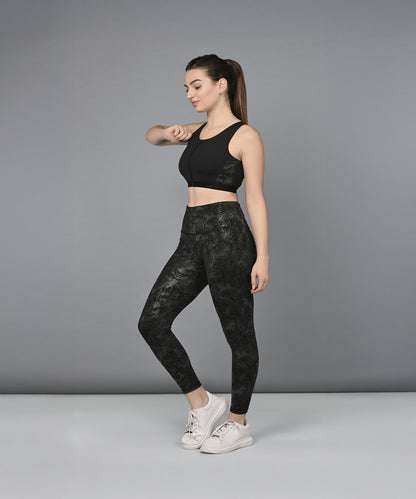A woman models the Zipped Sports Bra & Metallic Legging, standing sideways against a plain gray background.