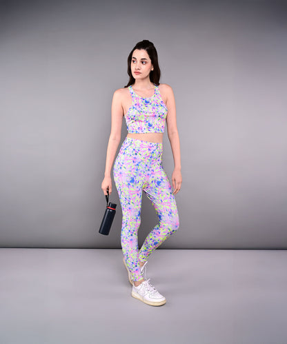A woman in a colorful workout outfit, featuring Multicolour Neon Leggings and holding a water bottle, stands against a plain gray background.