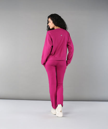 A woman wearing the Deep Pink Comfort Duo set and white sneakers stands facing away against a plain gray background.