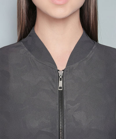 A woman shown from shoulders to lips wears a camouflage print tracksuit with a dark, textured V-neck collar and zipper.