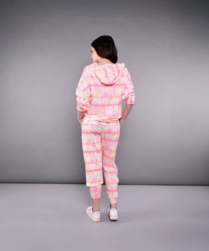A woman stands with her back to the camera, wearing the Comfort Fit Tie-Dye Sweatshirt With Joggers Set in pink and yellow.