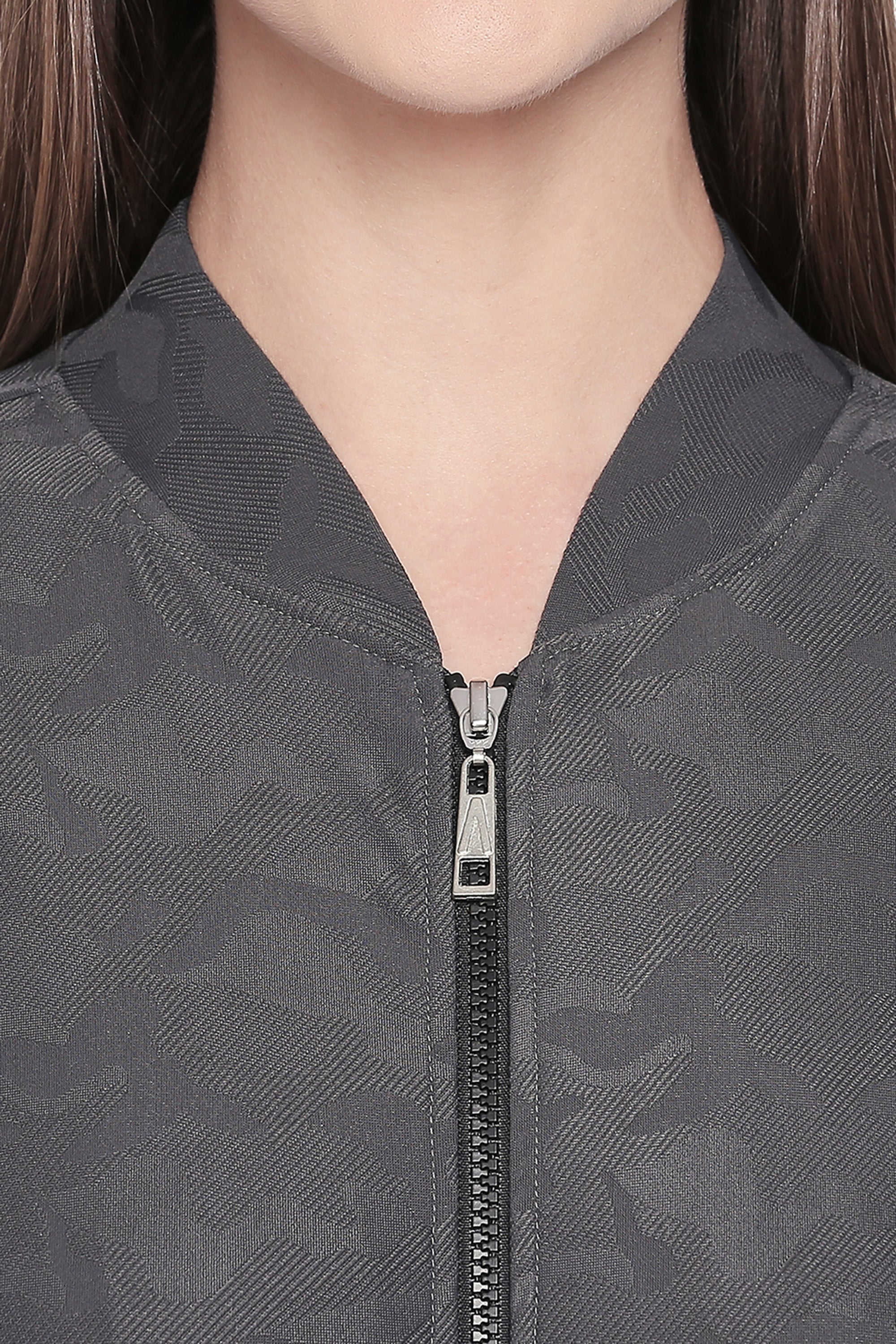 Close-up of a person wearing the Active Wear Printed Jacket in Grey from Tuna London, featuring a zipped front and crafted from textured polyester blend with a subtle pattern.