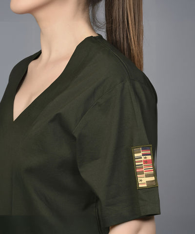 Wearing the Military Green Open Jacket & Yoga Pants with Bustiere set, a person in a dark green top featuring a military-style patch achieves a modern, active look.