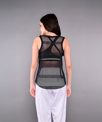 Woman wearing the Tuna Active Black Netted Tank Top and white pants, facing away from the camera against a gray background.