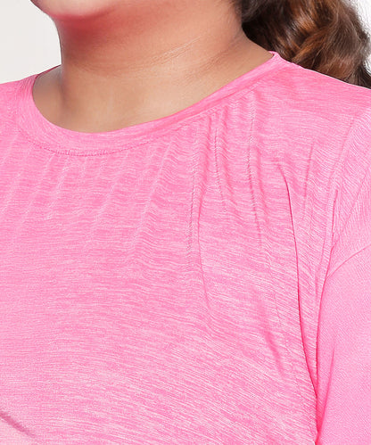 Wearing the Nova Sports Tee—a bright pink, textured athletic top with a round neckline—adds energy to any workout wardrobe.