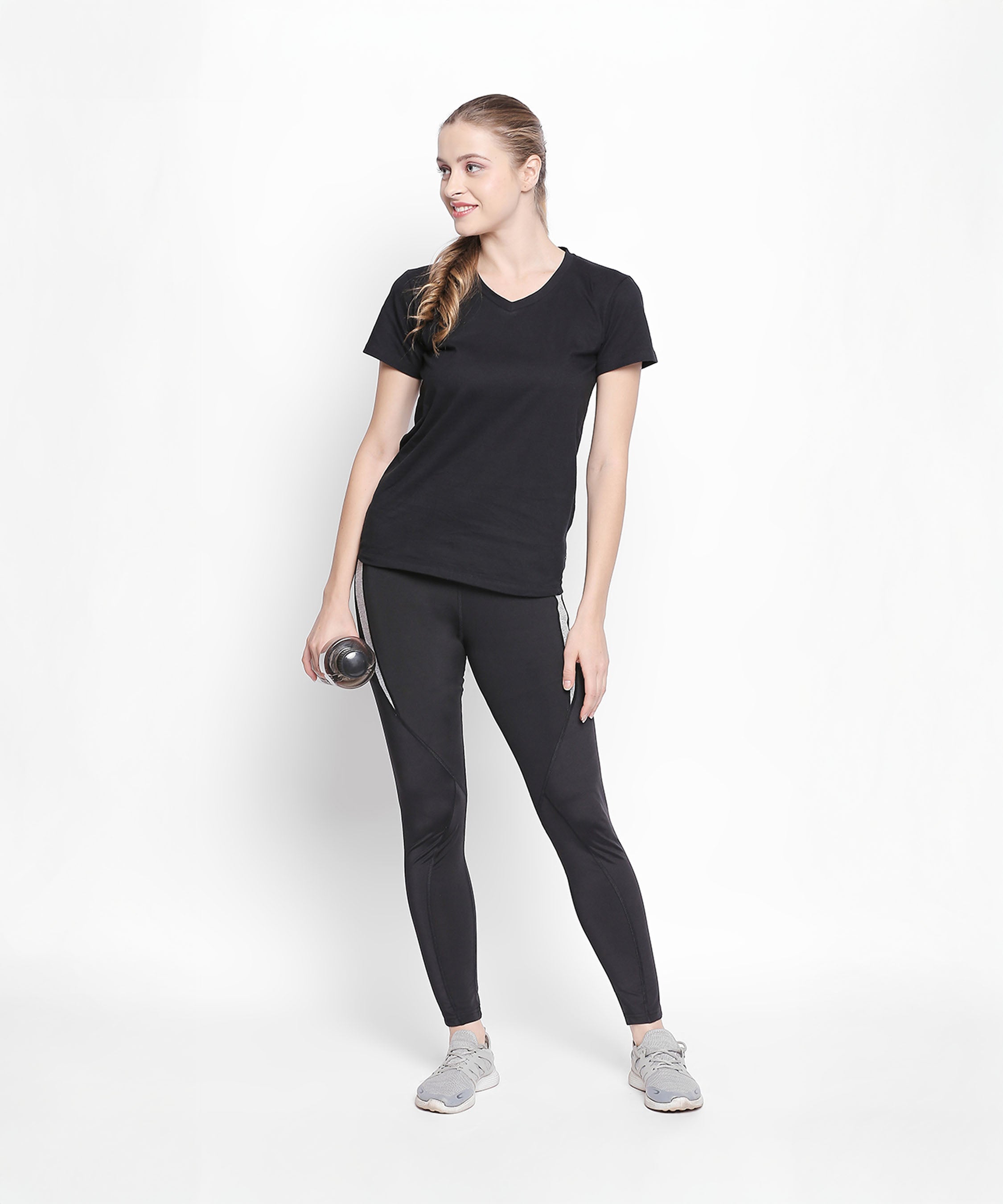 Woman wearing the Tuna London Sara Basic Sports Tee With Net Detailing for Women, holding a water bottle and smiling against a white background.