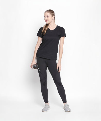 Woman wearing the Tuna London Sara Basic Sports Tee With Net Detailing for Women, holding a water bottle and smiling against a white background.