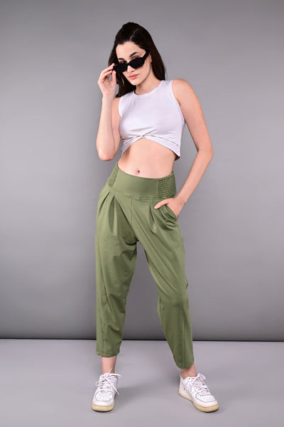 A woman wearing the White Twisted Crop Top with sunglasses, green pants, and sneakers poses against a plain gray background.