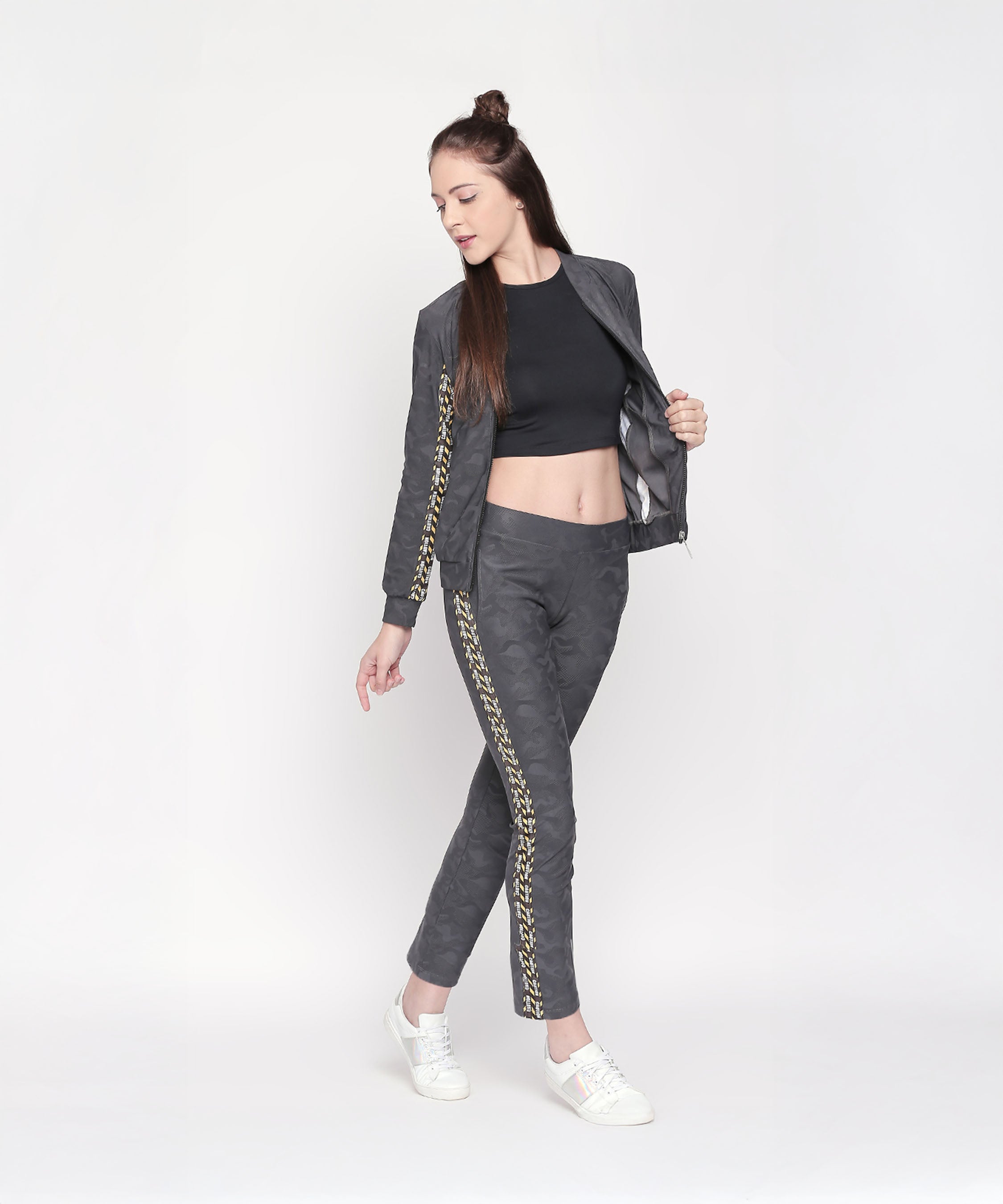 Woman in a Camouflage Print Tracksuit with a black crop top and white sneakers poses confidently against a white background.