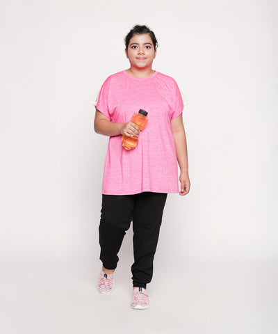 Woman wearing a pink shirt and Classic Joggers - Plus Size 02, holding a water bottle and walking towards the camera.