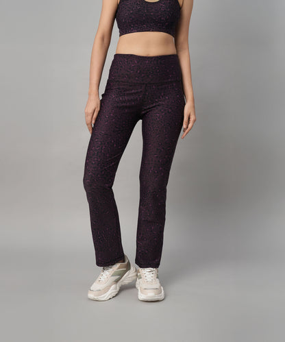 Woman in stylish Pink Animal Print Wide Legged Leggings paired with a matching activewear top and white sneakers, standing against a gray background.
