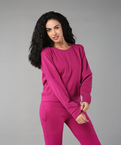 Woman with long curly hair wearing the Deep Pink Comfort Duo, standing against a plain gray background.
