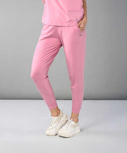 Person dressed in the Flamingo Pink Chic Ensemble—featuring buttery soft Joggers Cotton Lycra and a matching Racer Back top—paired with white sneakers, stands against a plain gray background.