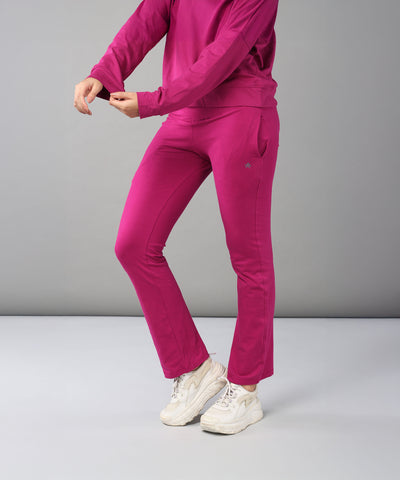 Wearing the Deep Pink Comfort Duo—cotton lycra joggers and top—paired with white sneakers, this person stands against a plain background.