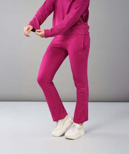 Wearing the Deep Pink Comfort Duo—cotton lycra joggers and top—paired with white sneakers, this person stands against a plain background.