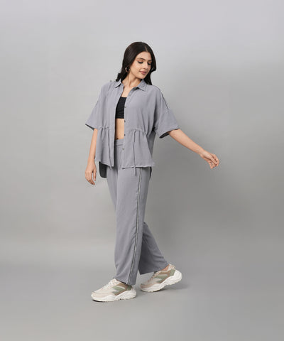 A woman wearing the Grey Tie Up Top with Loose Pants Cord Set and sneakers poses against a plain light gray background.