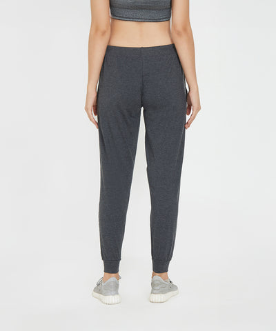A woman is shown from the back, standing against a white background, wearing Joggers - Ashtanga Series Grey and sneakers.