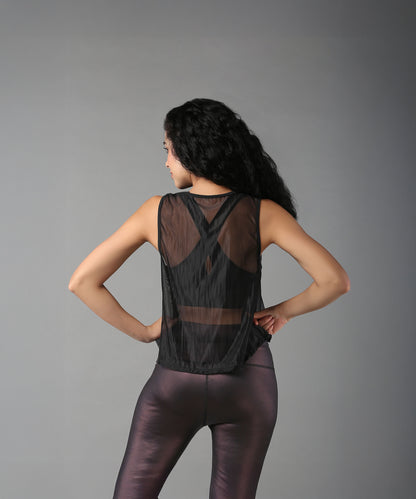 Woman models the Black Sheer Top, standing with hands on hips and facing away.