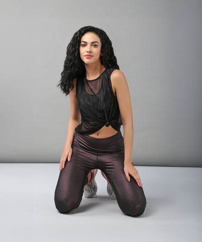 Woman with long curly hair kneeling on the floor, wearing a sexy Black Sheer Top and shiny dark leggings.