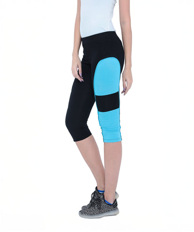 Woman wearing Capri TLC66 black cotton spandex capri pants with a blue panel and black sneakers, standing against a white background.