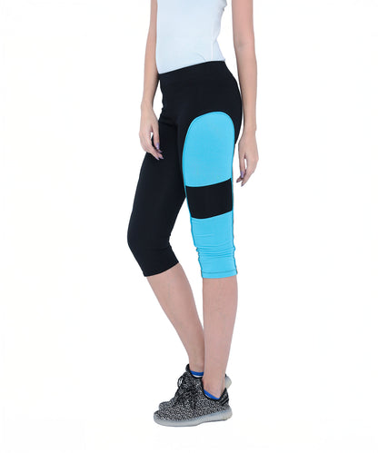 Woman wearing Capri TLC66 black cotton spandex capri pants with a blue panel and black sneakers, standing against a white background.