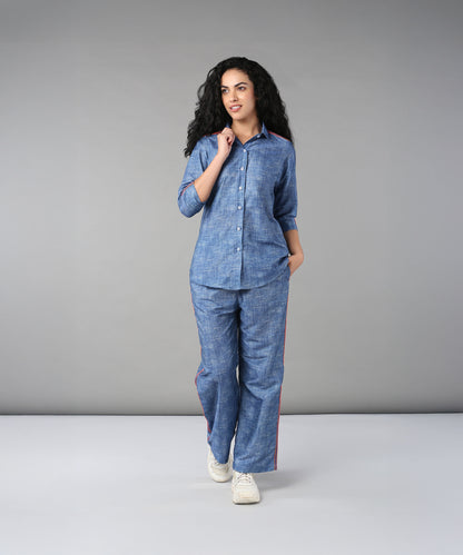 A woman with curly hair walks in a studio wearing the Denim Linen Co-Ord Set, featuring a relaxed fit shirt and matching pants.