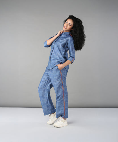 A woman with curly hair models the Denim Linen Co-Ord Set and white sneakers against a plain gray background.