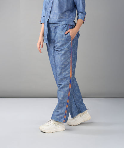 Model wears the Denim Linen Co-Ord Set featuring a relaxed fit shirt with side stripes, paired with white sneakers, standing against a gray background.
