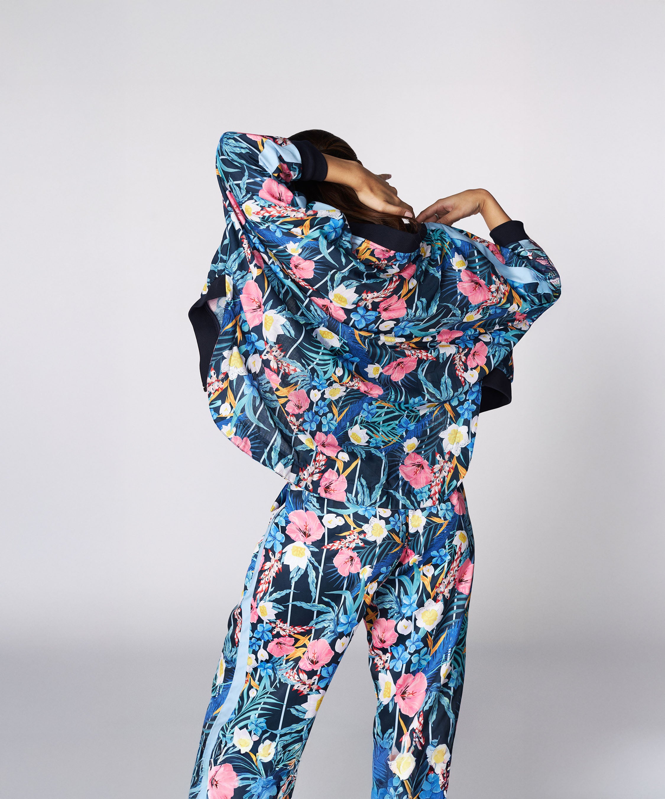 Person wearing the Tuna Active Floral Co-ord Set, showcasing its vibrant floral design while lifting their jacket and facing away from the camera against a plain background.