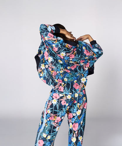 Person wearing the Tuna Active Floral Co-ord Set, showcasing its vibrant floral design while lifting their jacket and facing away from the camera against a plain background.