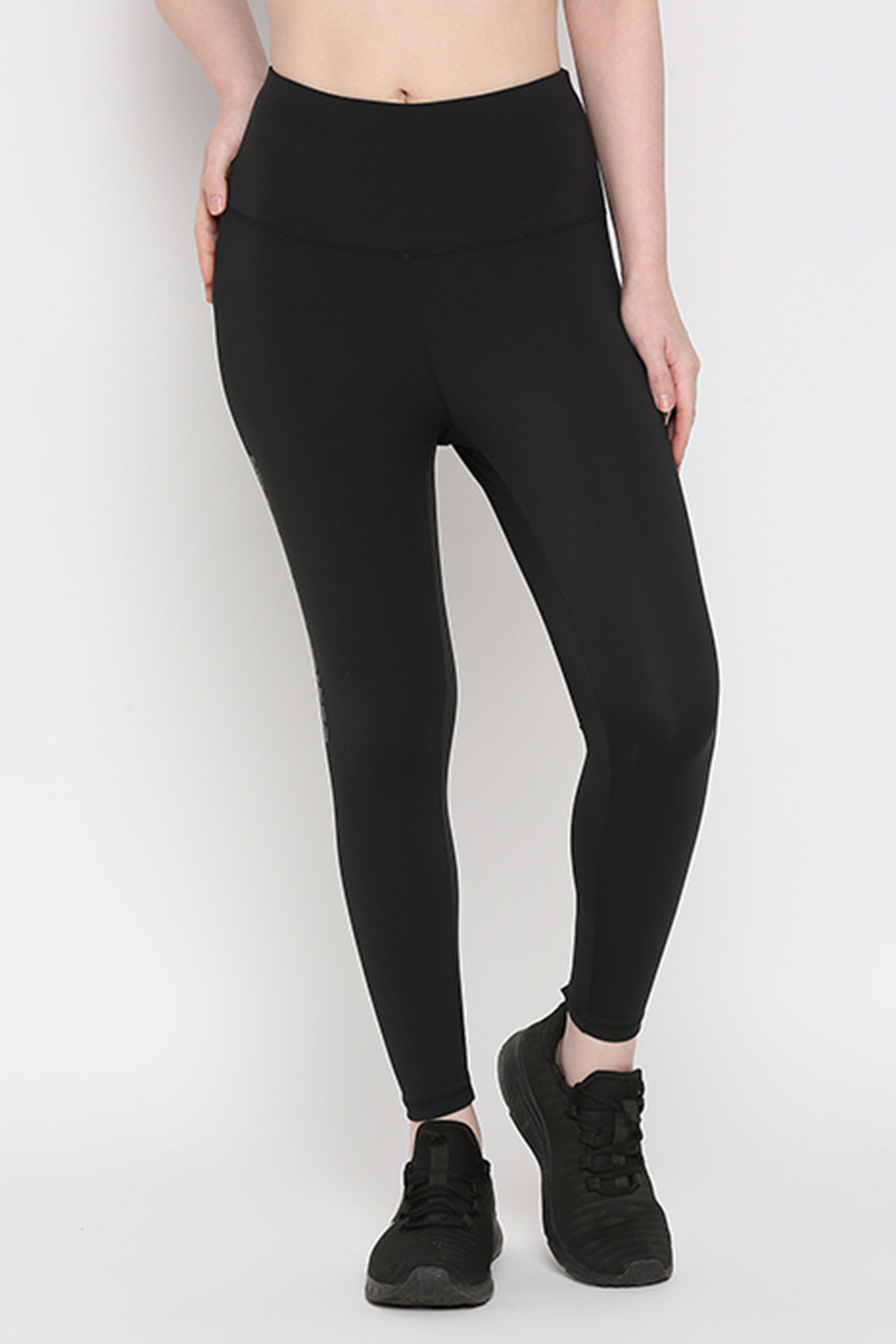 A person wears Tuna Active Black Leggings With Print, featuring high-waisted, superior quality stretchable fabric, and black sneakers against a plain white background—ideal for yoga, gym, or any fitness activity.