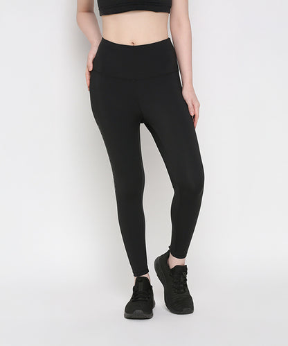 Woman wearing Tuna Active Black Leggings With Print and a black crop top with black sports shoes, standing against a plain white background—ideal for women’s gym wear or yoga leggings enthusiasts.