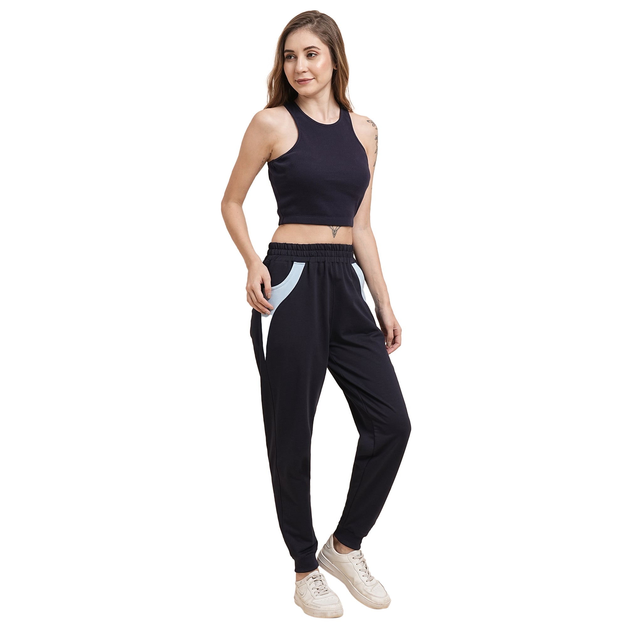 A woman wearing a Navy Blue Crop Top, paired with black joggers featuring light blue pockets and white sneakers, stands and smiles.