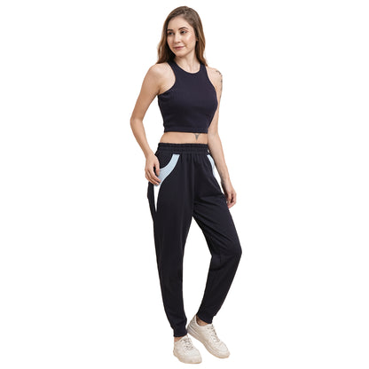 A woman wearing a Navy Blue Crop Top, paired with black joggers featuring light blue pockets and white sneakers, stands and smiles.