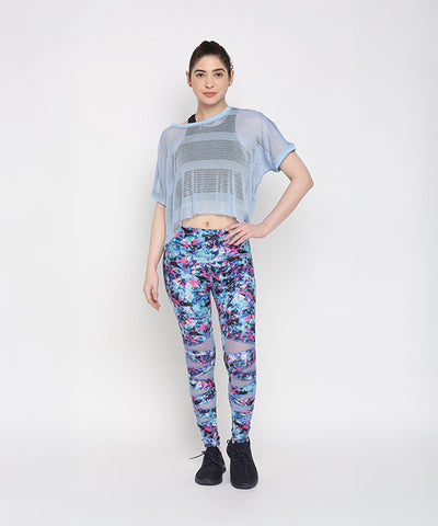 Woman wearing the Blue Netted Top and stylish leggings poses against a plain white background, highlighting a trendy sporty look.