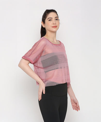 A woman models the Pink Netted Top with stylish leggings, striking a pose against a plain white background to showcase a sporty look.