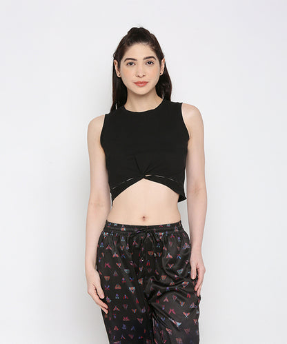 A woman wears the Black Twisted Crop Top with black printed pants, standing against a white background.