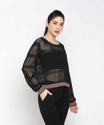 A woman models the Black Netted Top, featuring striped cuffs and a sheer black design for a sporty look against a plain white background.
