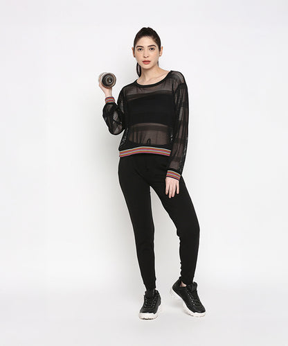 A woman showcases the Black Netted Top, paired with leggings and holding a dumbbell, striking a sporty pose against a plain white background.