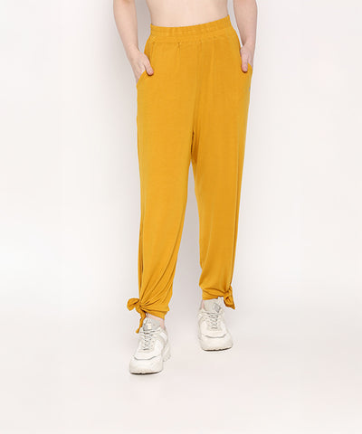 A person wearing the Mustard Chic Set, featuring mustard yellow Cotton Modal Trackpant joggers with a soft elasticated waistband and white sneakers, stands with hands in pockets.