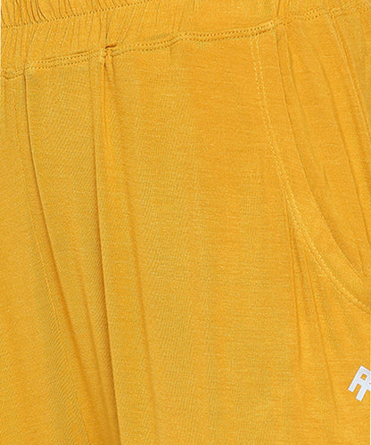 Close-up of the Mustard Chic Set trackpant in yellow, featuring a pocket and elastic waistband.