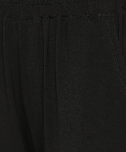 Close-up of the Comfy Black Set with Side Sparkle showing its black, loose fit track pant fabric, elastic waistband, and visible stitching by the pocket.