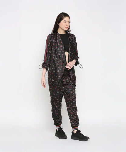A woman stands against a plain white background wearing Tuna Active Butterfly Joggers with black sneakers, styled as part of a black co-ord set.