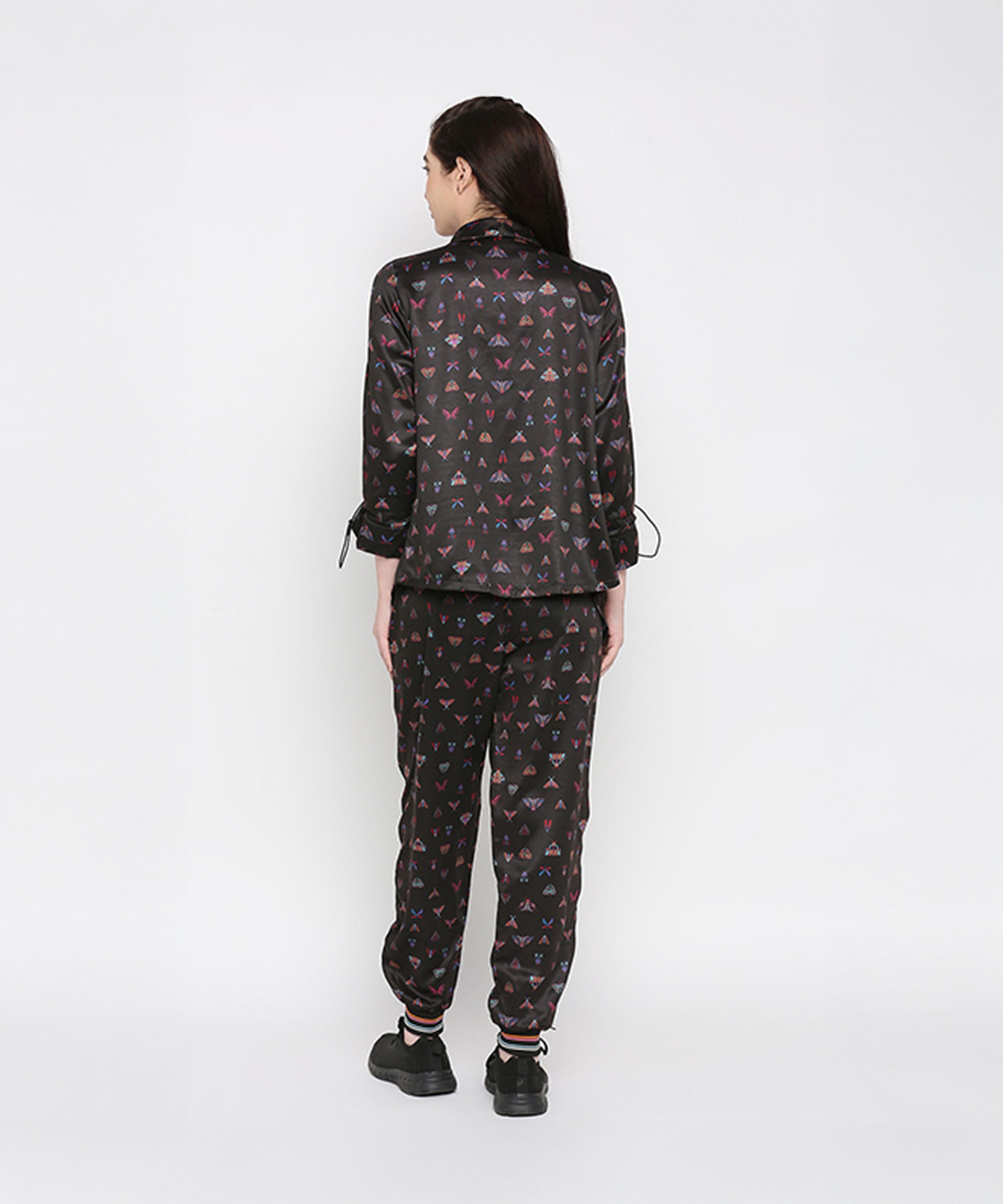 A woman stands with her back to the camera, wearing the Tuna Active Butterfly Joggers with a matching black printed top.