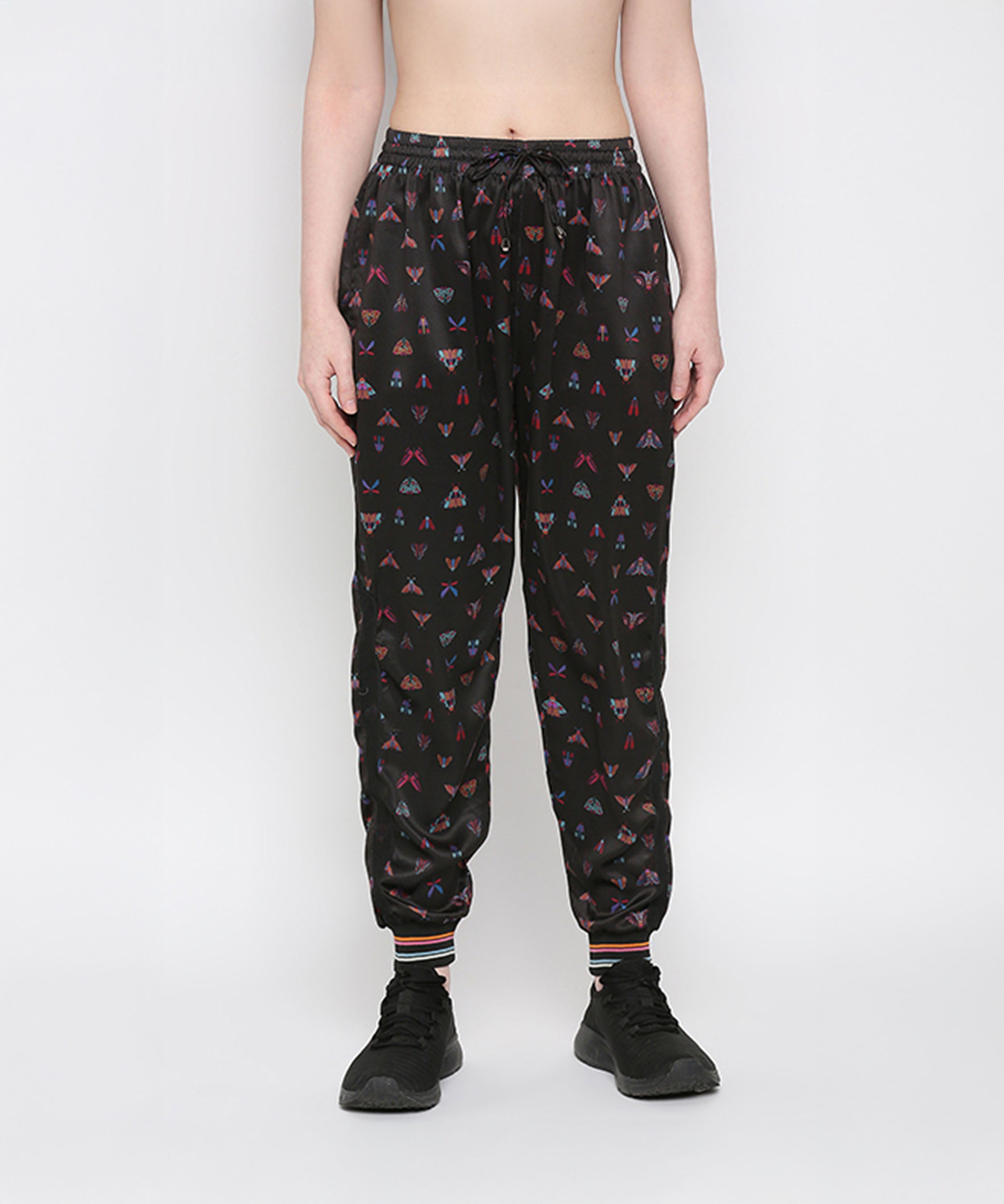 Wearing Tuna Active Butterfly Joggers with colorful triangle patterns and black sneakers, standing against a plain background.