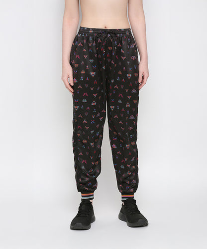 Wearing Tuna Active Butterfly Joggers with colorful triangle patterns and black sneakers, standing against a plain background.