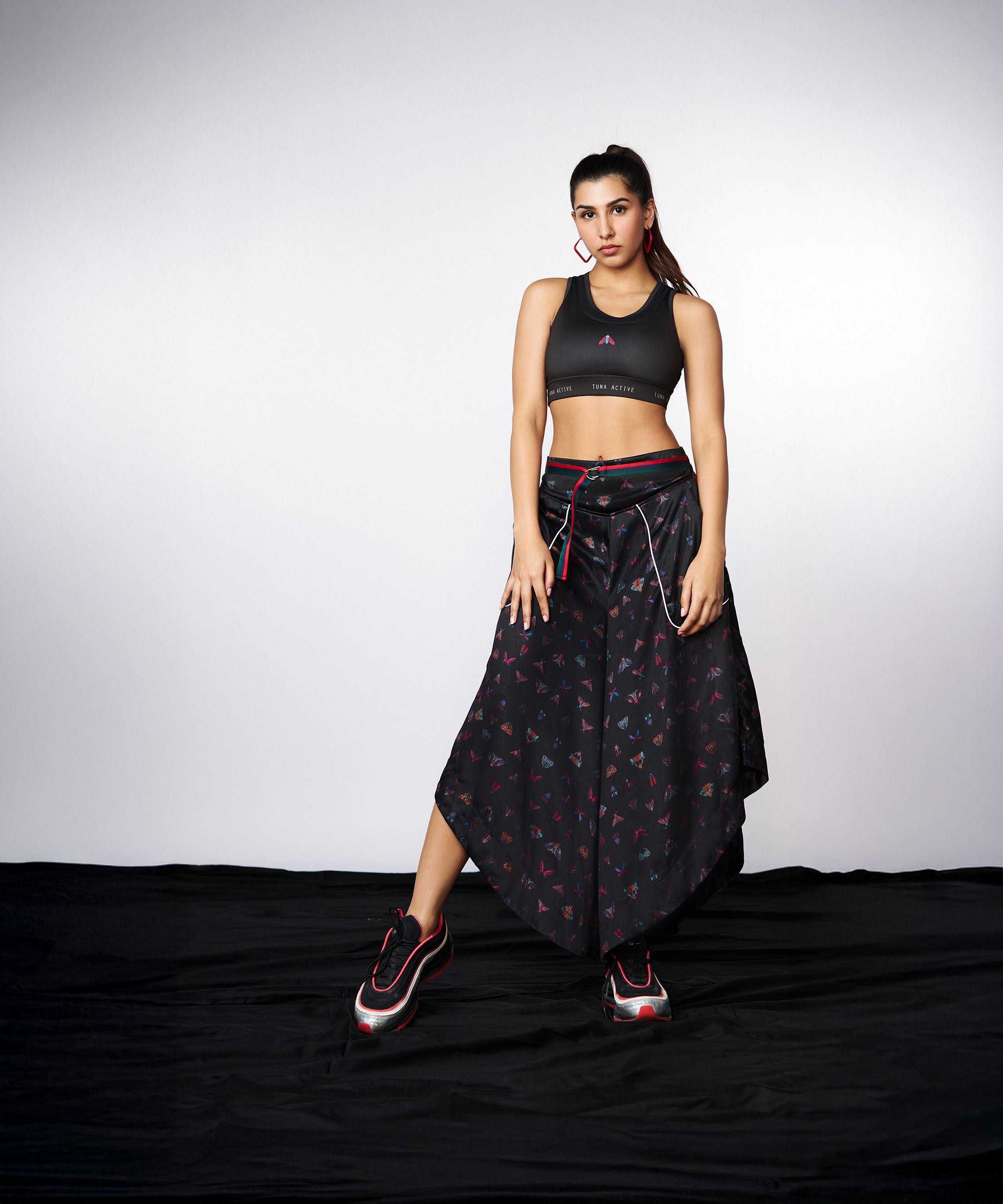 Woman in the Tuna Active Co-ord Set—yoga pants with cargo pockets and a matching sporty jacket—stands on a black cloth against a gray background.