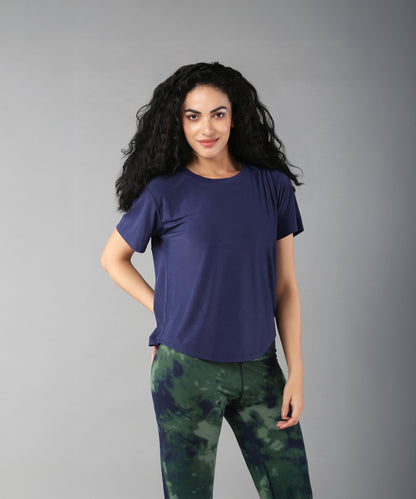 A woman with long curly hair wears the Functional - Blue Soft T Shirt, made from durable, comfortable materials, standing against a plain gray background.