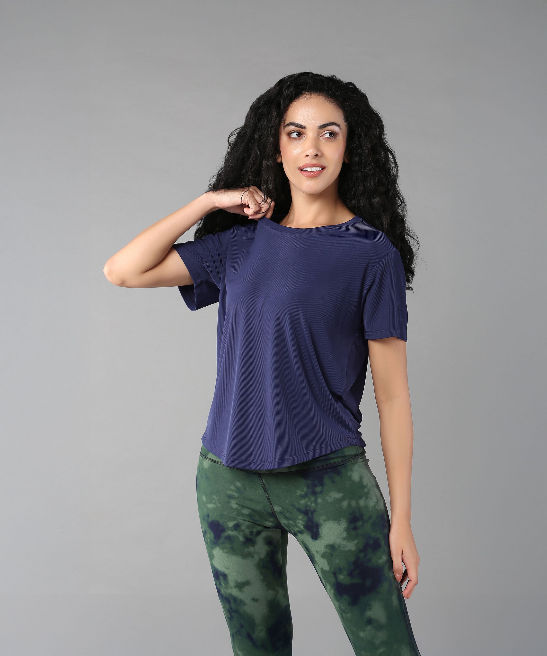 Woman with long curly hair wears the Functional - Blue Soft T Shirt, made from durable, comfortable materials, posing against a gray background.
